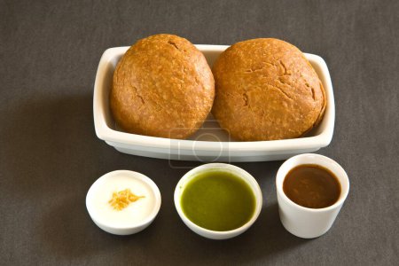 Foto de Snack indio frito shahi khasta kachori chaat en tazón con yogur cilantro verde y chutney de tamarindo sobre fondo negro 23-abril-2010 - Imagen libre de derechos