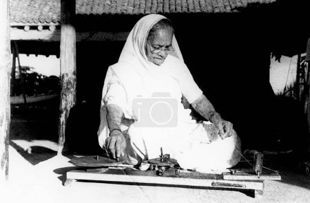 Téléchargez les photos : Kasturba Gandhi tournant sur la roue Kisan à l'ashram de Sevagram, 1940 - en image libre de droit