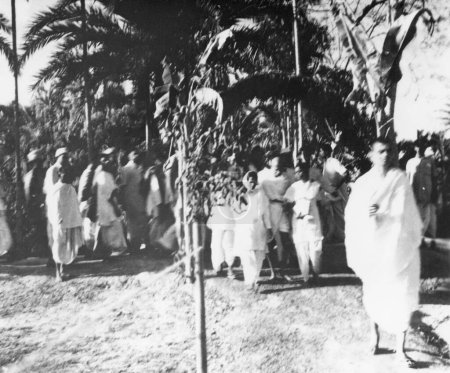 Foto de Mahatma Gandhi, caminando con Amtus Salam, Abha Gandhi y otros a través de la zona afectada por los disturbios de Noakhali Bengala Oriental - Imagen libre de derechos