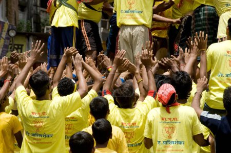 Foto de Ayudando a las manos a apoyar la pirámide humana tratando de romper dahi handi en el festival janmashtami en dadar, Bombay, Mumbai, Maharashtra, India - Imagen libre de derechos