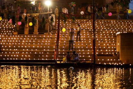 Foto de Varios cientos de lámparas o diyas encendidas en ghat en vísperas del dios dev diwali celebrando diwali en las orillas del río sagrado Ganga, Varanasi, Uttar Pradesh, India - Imagen libre de derechos