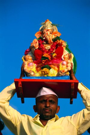 Téléchargez les photos : Homme tenant statue sur son front pour Ganesh ganpati Festival Elephant head Lord immersion, bomay mumbai, maharashtra, Inde - en image libre de droit