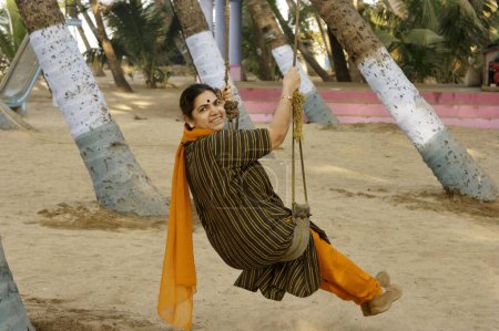 Photo for Woman on swing at coconut tree, Murud Janjira, District Raigad, Maharashtra, India - Royalty Free Image
