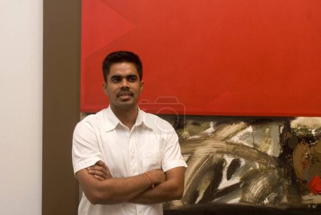 Photo for South Asian Indian painter Nitish Bhattacharya against the backdrop of his painting, Bombay Mumbai, Maharashtra, India - Royalty Free Image