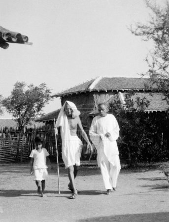 Foto de Mahatma Gandhi caminando con el Dr. Das y un niño en el Ashram Sevagram, 1940 - Imagen libre de derechos