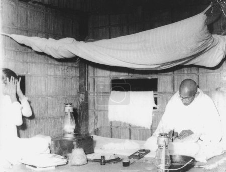 Foto de Mahatma Gandhi en el trabajo en la tenue luz de una lámpara de queroseno en Bengala Occidental, India, diciembre 1946 - Imagen libre de derechos