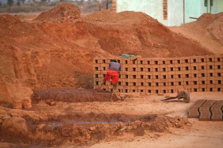 Téléchargez les photos : Travailleur seul travaillant sur un mélange pour fabriquer des briques dans une usine de briques à Jharkhand ; Inde - en image libre de droit