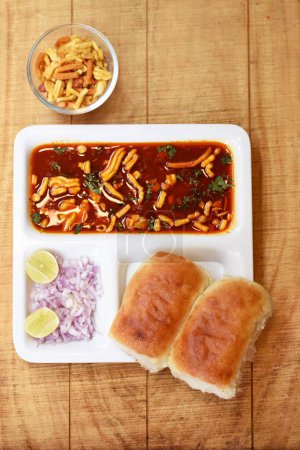 Photo for Indian delicious Misal Pav with onion and coriander spread on top of curry wheat bread - Royalty Free Image