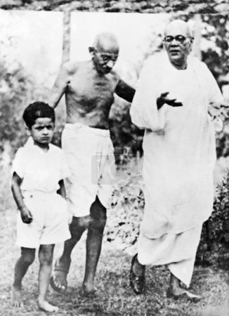 Photo for Mahatma Gandhi walking with a boy and Sharad Bose, 1945 - Royalty Free Image