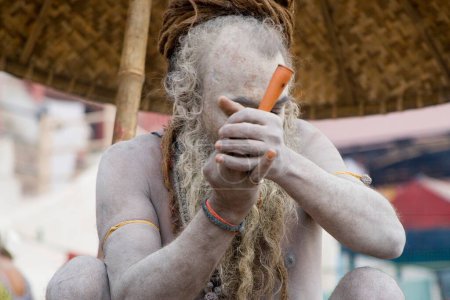 Hindu-Heiliger Naga Baba Shivdasgiri raucht Tabak in Varanasi am Ganga-Fluss; Uttar Pradesh; Indien MR707A