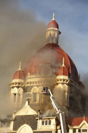 Foto de El humo emite desde el Hotel Taj Mahal y oficiales de bomberos posponiendo el fuego durante el ataque terrorista de Deccan Mujahideen; Bombay Mumbai; Maharashtra; India 27-noviembre2008 - Imagen libre de derechos