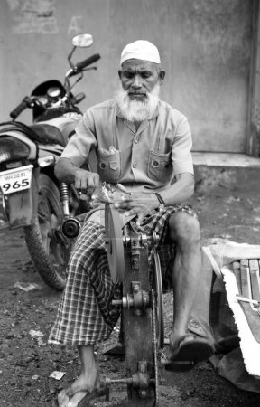 Téléchargez les photos : Couteau à aiguiser vieil homme sur la machine dans le bidonville de Dharavi, Bombay Mumbai, Maharashtra, Inde - en image libre de droit
