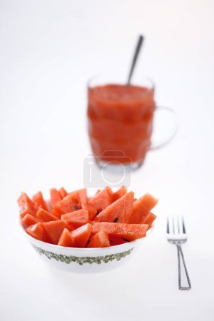Téléchargez les photos : Fruits, Melon d'eau Latin Citrullus Lanatus jus dans une tasse avec des morceaux dans un bol avec fourchette et cuillère - en image libre de droit