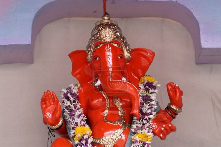 Téléchargez les photos : Idole de couleur écarlate du Seigneur Ganesh avec décoration simple ; adoration pour la fête Ganapati ; dieu tête d'éléphant de l'hindouisme ; Pune ; Maharashtra ; Inde - en image libre de droit