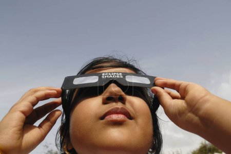 Photo for A young girl watches the partial solar eclipse by wearing a protected filter on 1st August 2008 in Bombay Mumbai, Maharashtra, India - Royalty Free Image