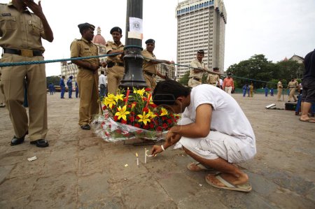 Téléchargez les photos : Un homme allume une bougie devant l'hôtel Taj Mahal et rend hommage aux victimes d'un attentat terroriste perpétré par Deccan Moudjahidine le 26 novembre 2008 à Bombay Mumbai, Maharashtra, Inde - en image libre de droit