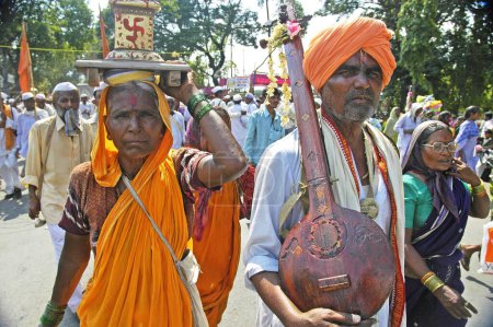 Téléchargez les photos : Couple dévot avec l'usine Ektara et Tulsi marchant vers le temple Vitthala ; Foire Pandharpur ; Pandharpur ; Maharashtra ; Inde - en image libre de droit