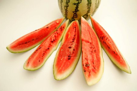 Fruits ; One full watermelon with light and dark green stripes with five cut slices showing watery red pulp and black seeds ; Pune ; Maharashtra ; India
