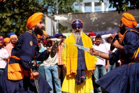 Téléchargez les photos : Guerriers nihang ou sikhs effectuant des cascades avec épée et bouclier lors des célébrations Hola Mohalla à Anandpur sahib dans le district de Rupnagar ; Punjab, Inde - en image libre de droit