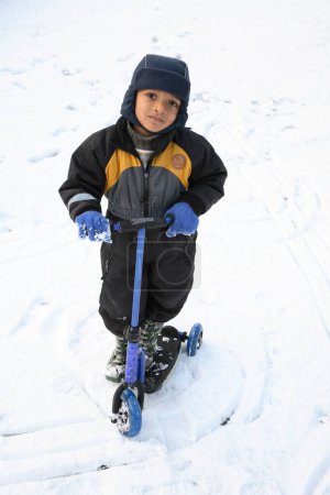 Foto de Niño pequeño montando su triciclo en la nieve, Suecia - Imagen libre de derechos