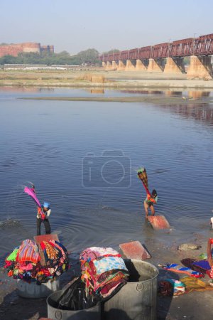 Téléchargez les photos : Blanchisserie en plein air laver les vêtements dans Yamuna River en arrière-plan Agra Fort ; Agra ; Uttar Pradesh ; Inde - en image libre de droit
