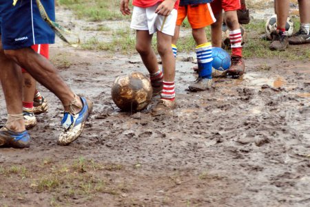 Foto de Niños indios del sur de Asia jugando, practicando, disfrutando con la pelota a pie durante la temporada de monzones, India - Imagen libre de derechos