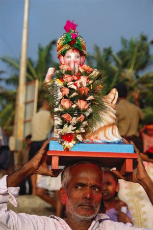 Photo for Man holding idol on his forehead On Ganesh ganpati Festival Elephant head Lord immersion , dadar , bombay mumbai, maharashtra , india - Royalty Free Image