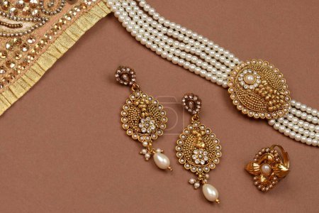 Foto de Joyería de perlas sobre fondo marrón, bufanda dorada, pulsera de perlas fondo de joyería, collar de perlas, pendientes de perlas, anillo de dedo. Estilo, moda y diseño de joyas. joyería tradicional india - Imagen libre de derechos
