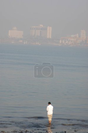 Téléchargez les photos : Homme jouant le matin Pooja au bord de la mer, Inde - en image libre de droit