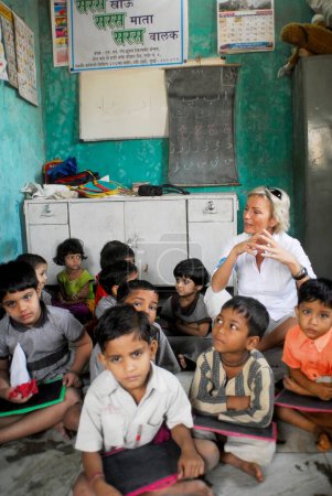Photo for Sabine Christiansen in conversation with children at Amrae an NGO at Nehru Nagar, Golibar Slum ;Santacruz ;Bombay Mumbai, Maharashtra, India - Royalty Free Image