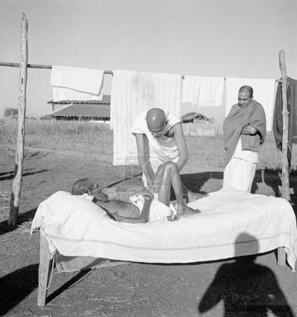 Téléchargez les photos : Mahatma Gandhi, donnant son massage quotidien de 15 min au lépreux Parchure Shastri à l'Ashram de Sevagram, 1940, travailleur shankaran à Sushila Nayars Kasturba Gandhi Hospital près de l'Ashram de Sevagram - en image libre de droit