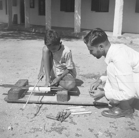 Foto de Niño usando torno giratorio portátil aplicando laca a una madera wringtinforia, pintando juguetes de laca, Channapatna, Karnataka, India - Imagen libre de derechos