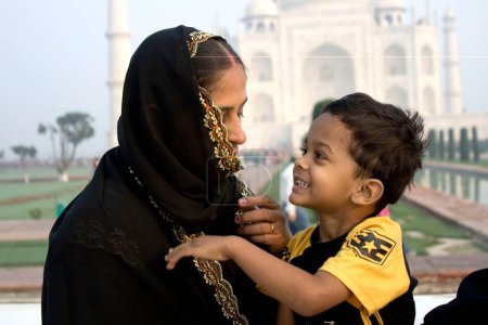 Photo for A Muslim mother child in front of mogul monument Taj Mahal seven wonder of the world constructed by emperor Shah Jahan ; Agra ; Uttar Pradesh ; India - Royalty Free Image