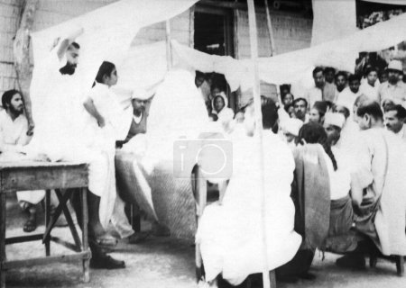 Foto de Mahatma Gandhi, hablando con la gente mientras toma un baño de sol en la aldea Dasgharia Noakhali Bengala Oriental donde Kanu Gandhi se quedó - Imagen libre de derechos
