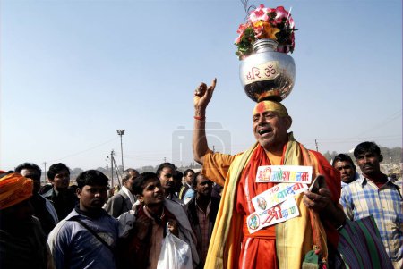 Téléchargez les photos : Un saint sadhu équilibre un bocal en acier inoxydable avec des fleurs sur sa tête, Ardh Kumbh Mela, l'un des plus grands festivals religieux au monde à Allahabad, Uttar Pradesh, Inde - en image libre de droit