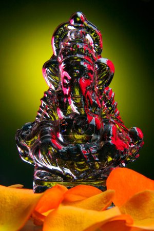Photo for Table Top Studio shot of Glass Idol of Lord Ganesh Ganapati , Elephant headed God with Rose Petals of yellow color - Royalty Free Image