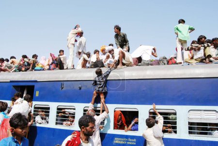 Téléchargez les photos : Homme traînant un enfant essayant de monter sur le toit du train sur la gare, Jodhpur, Rajasthan, Inde - en image libre de droit