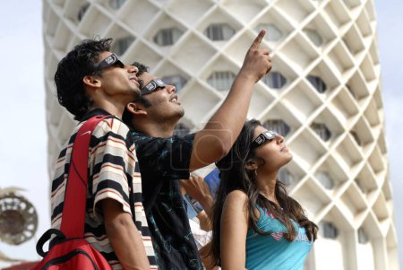 Téléchargez les photos : Trois adolescents regardent l'éclipse solaire partielle en portant un filtre protégé le 1er août 2008 au Nehru Centre à Bombay Mumbai, Maharashtra, Inde - en image libre de droit