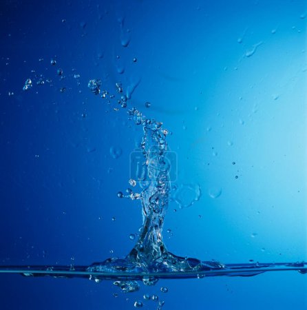Foto de Concepto; Salpicadura de gota de agua con fondo azul - Imagen libre de derechos