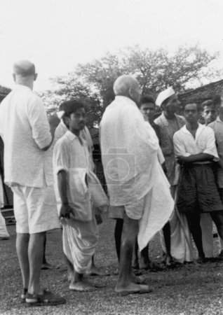 Foto de Mahadev Desai, Dhirendra Chatterjee hermano de Abha Gandhi, Mahatma Gandhi y otros en Sevagram Ashram, 1941 - Imagen libre de derechos