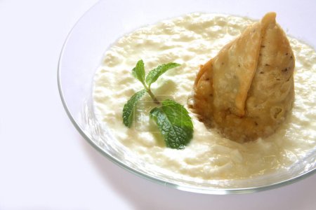Foto de Comida rápida, samosa con cuajada y hojas de menta en tazón sobre fondo blanco - Imagen libre de derechos