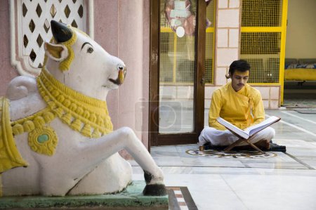 Foto de Hombre leyendo libro sagrado frente al templo Hanuman, Mathura, uttar pradesh, India, Asia - Imagen libre de derechos