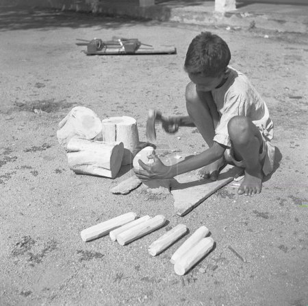 Foto de Niño usando torno giratorio portátil aplicando laca a una madera wringtinforia, pintando juguetes de laca, Channapatna, Karnataka, India - Imagen libre de derechos