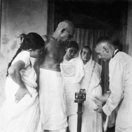 Foto de Mahatma Gandhi de pie en una balanza de pesaje durante su ayuno Belia Ghat, 1946 Abha Gandhi, Manu Gandhi También se puede ver Sharad Bose, India - Imagen libre de derechos