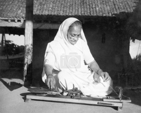 Foto de Kasturba Gandhi girando en Kisan Spinning Wheel en Sevagram Ashram, 1940 - Imagen libre de derechos