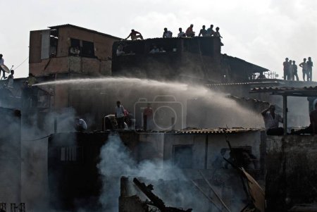 Téléchargez les photos : Pompiers aspergeant le feu avec un tuba dans les bidonvilles de Behrampada ; Bandra ; Bombay Mumbai ; Maharashtra ; Inde 18-juin-2009 - en image libre de droit