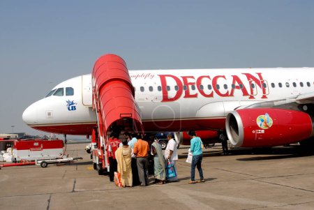 Photo for Passenger arriving in red and white deccan aeroplane at airport. India - Royalty Free Image