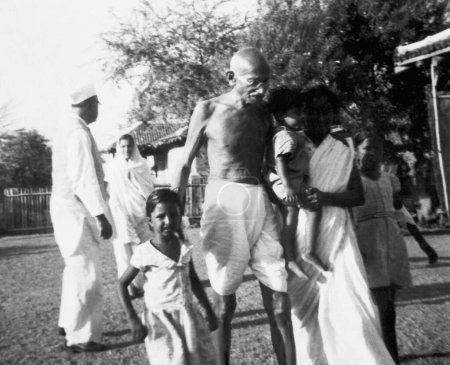 Foto de Mahatma Gandhi caminando con su nieta Saraswati, su hijo Shanti y otros en Sevagram Ashram, 1940 - Imagen libre de derechos