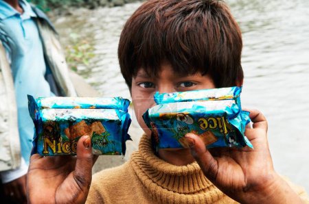 Foto de Chico mostrando paquetes de galletas empapadas en aceite debido a que el buque portacontenedores chitra chocó en el mar Bombay Mumbai, Maharashtra, India, 9 de agosto de 2010 - Imagen libre de derechos