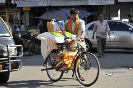 Téléchargez les photos : Homme portant des sacs à bagages à vélo à Mumbai Maharashtra Inde - en image libre de droit